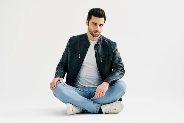 Handsome trendy man sitting on floor isolated on white studio background - Fotoğraf, Görsel