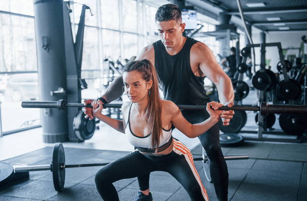 Jeunes sportifs faisant des exercices avec des poids lourds ensemble dans la salle de gym. - Photo, image