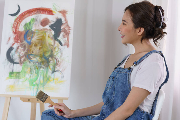 Creative of art concept, Young asian woman hold paint brush and happy to look on art masterpiece. - Fotografie, Obrázek