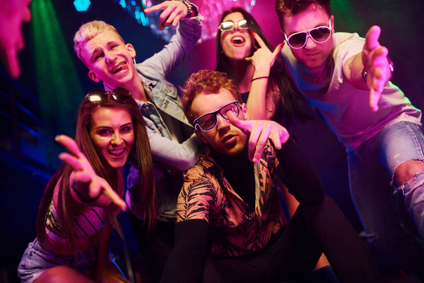 Going crazy and posing for the camera together. Young people is having fun in night club with colorful laser lights. - Foto, imagen
