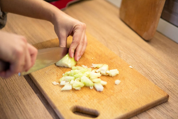 τεμαχισμός κρεμμυδιού σε κομμένη σανίδα close up οικιακή κουζίνα - Φωτογραφία, εικόνα