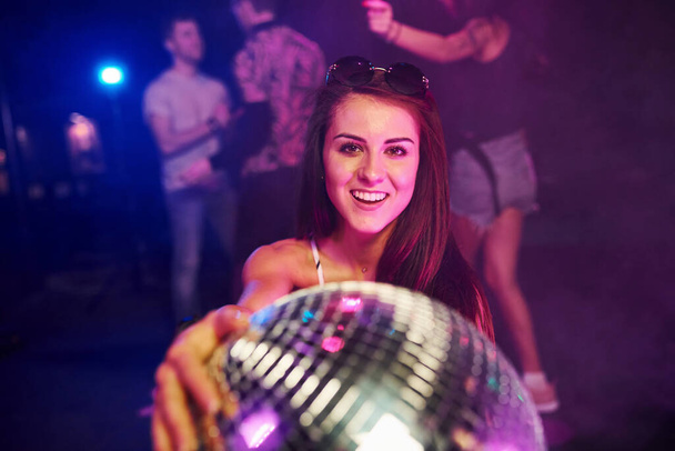 Girl sitting inside of night club with party ball in hands. - Фото, зображення