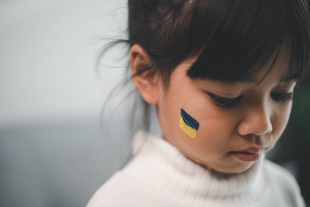 Ein Kind mit der Fahne der Ukraine weint. Traurigkeit sehnt sich nach Hoffnung. Kindertränen aus dem Krieg. Evakuierung von Zivilisten. Freiheit für die Ukraine - Foto, Bild