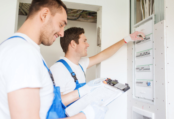 builders with clipboard and electrical panel - Foto, Imagen