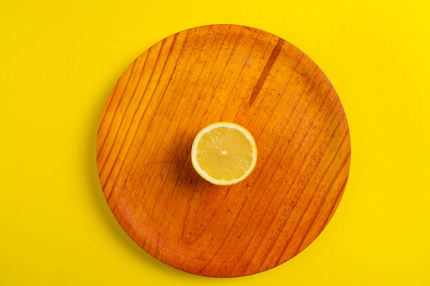 Top view of halved lemon on wooden plate isolated on yellow background, healthy food concept - Fotografie, Obrázek