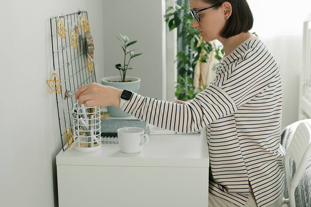 Freelancer woman with dark short hair in striped shirt, wearing glasses working at office desk table. Lifestyle, small business concept - Foto, imagen