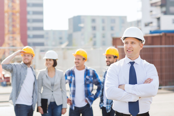 group of smiling builders in hardhats outdoors - Foto, Imagem