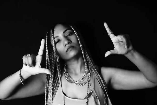Female rapper gesturing over black background - Foto, imagen