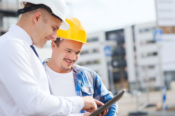 smiling builders in hardhats with tablet pc - Valokuva, kuva