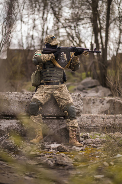 Ukrainian soldier of the Armed Forces of Ukraine sits taking aim - Фото, зображення