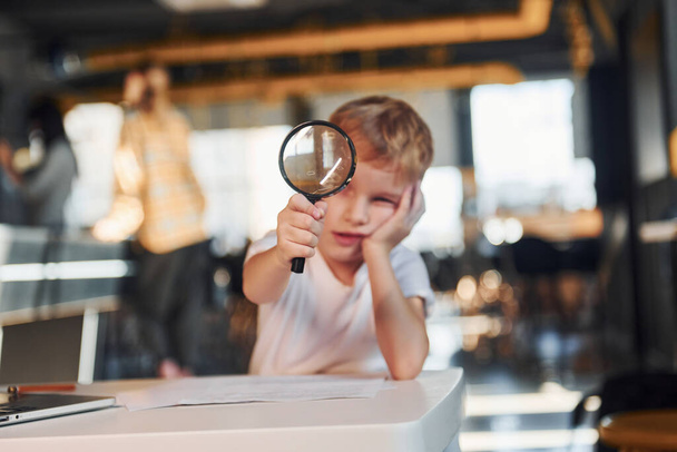 Smart child in casual clothes with laptop on table have fun with magnifying glass. - Valokuva, kuva