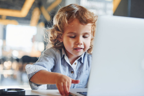 Smart child in casual clothes using laptop for education purposes or fun. - Foto, Imagen
