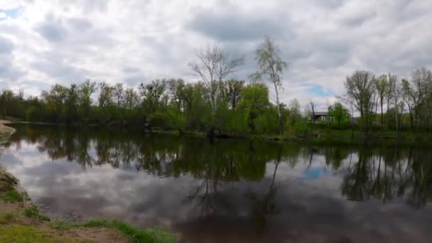 Timelapse of moving clouds. Dynamic footage of clouds over a river in northern Europe. Beach near the lake. People are walking along the beach. Panoramic timelapse of a landscape in motion.  - Felvétel, videó