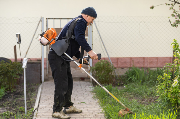 Man mowing the lawn in his garden. Gardener cutting the grass. Lifestyle. - Fotó, kép