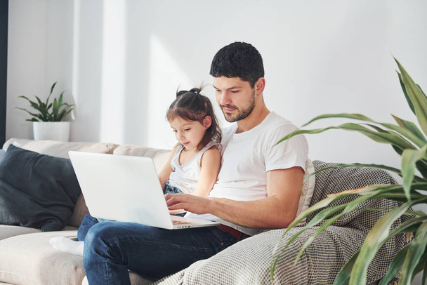 Happy father with his daughter spending free time with laptop at home together. - Φωτογραφία, εικόνα