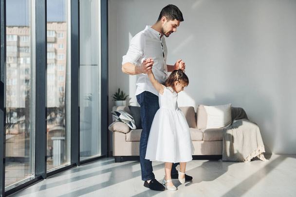Happy father with his daughter in dress learning how to dance at home together. - Photo, image