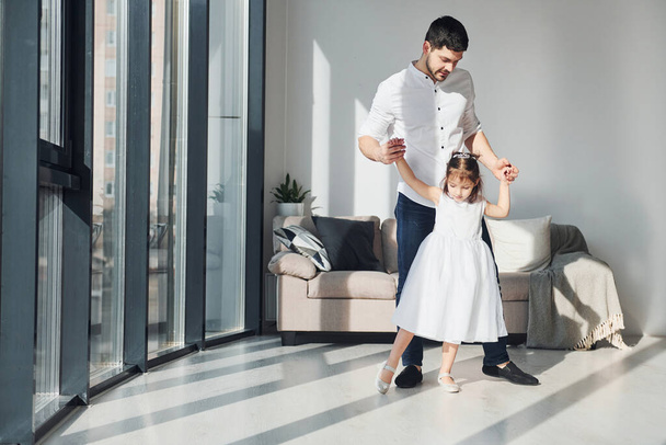 Happy father with his daughter in dress learning how to dance at home together. - Foto, immagini
