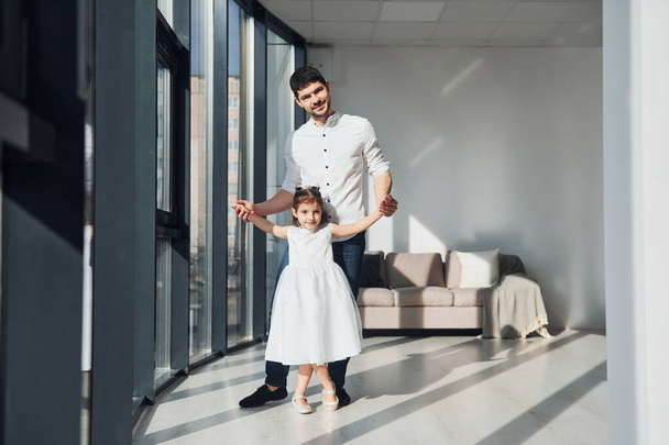 Happy father with his daughter in dress learning how to dance at home together. - Zdjęcie, obraz