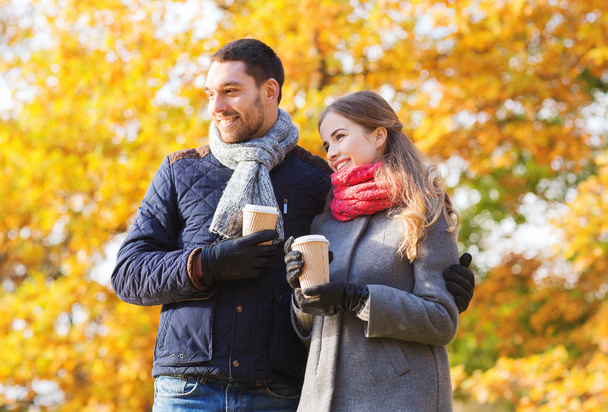smiling couple with coffee cups in autumn park - Zdjęcie, obraz