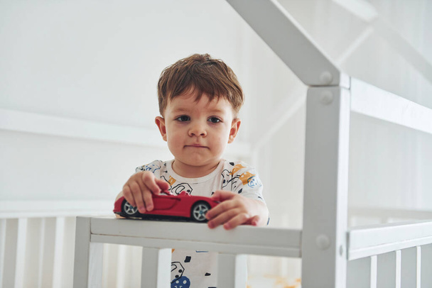 Cute little boy resting and have fun with car indoors in the bedroom. - Fotó, kép