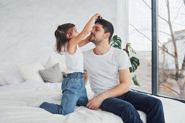 Happy father with his daughter having fun with comb at home together. - Foto, Bild