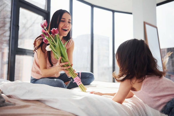 Daughter congratulates mother with holiday and gives bouquet of flowers. - Foto, Bild