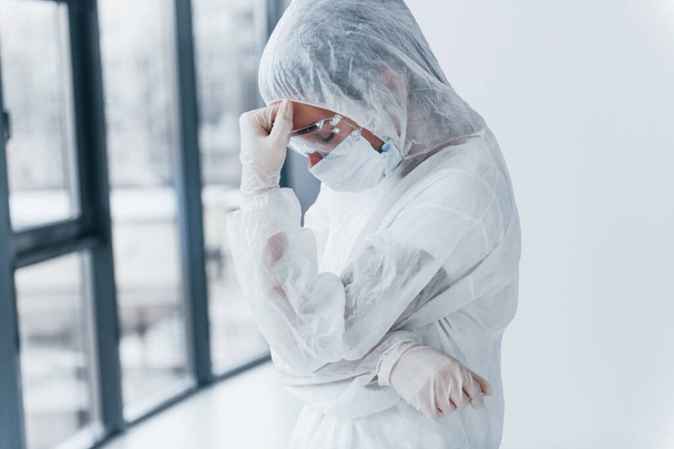 Feeling bad, tired and depressed. Portrait of female doctor scientist in lab coat, defensive eyewear and mask. - Fotografie, Obrázek