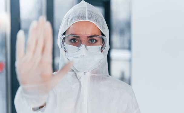 Stop the virus sign. Portrait of female doctor scientist in lab coat, defensive eyewear and mask. - Photo, image