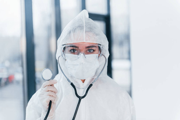 With stethoscope. Portrait of female doctor scientist in lab coat, defensive eyewear and mask. - Fotografie, Obrázek