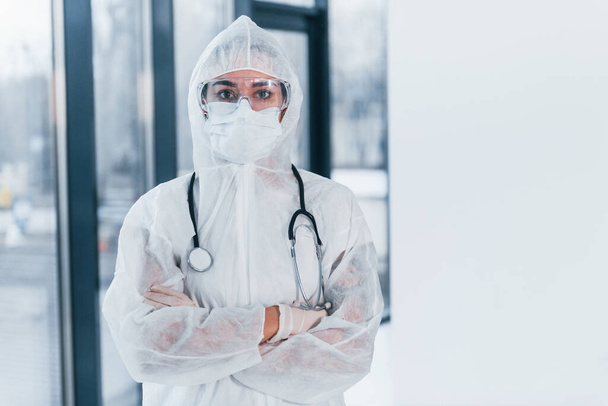 With stethoscope. Portrait of female doctor scientist in lab coat, defensive eyewear and mask. - Foto, afbeelding