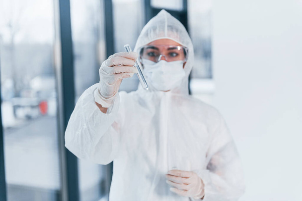 Holds test tube. Portrait of female doctor scientist in lab coat, defensive eyewear and mask. - Foto, Imagem