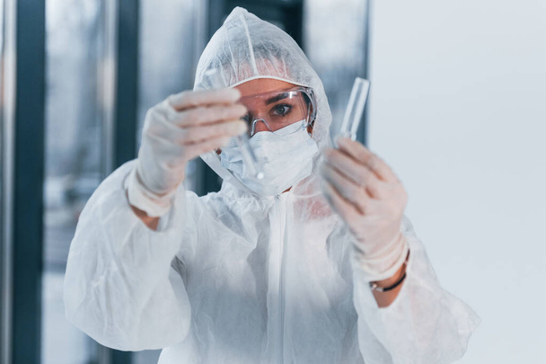 Holds test tubes. Portrait of female doctor scientist in lab coat, defensive eyewear and mask. - Foto, Bild