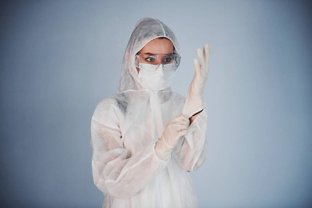 Portrait of female doctor scientist in lab coat, defensive eyewear and mask wearing gloves. - Fotó, kép