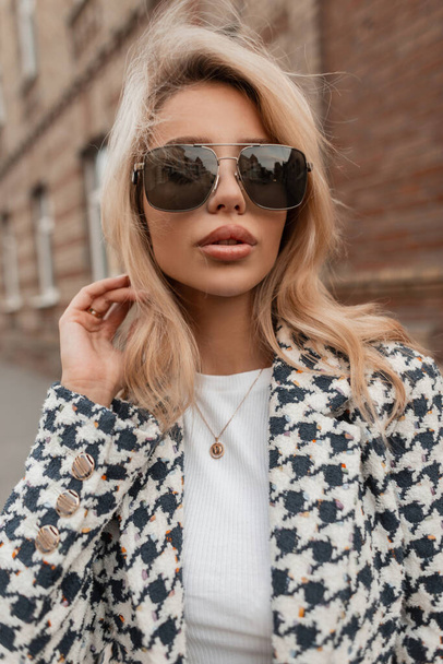 Beautiful blonde woman with sunglasses walks on the street. Urban female style outwear - Photo, Image