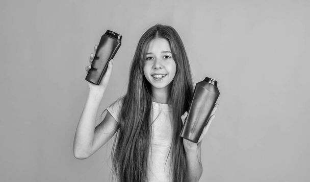 Making hair look magical. beauty. wash and rinse. happy teen girl presenting cosmetic product. shampooing hair in salon. daily habits and personal care. child use shampoo in bottle. hair conditioner - Фото, зображення