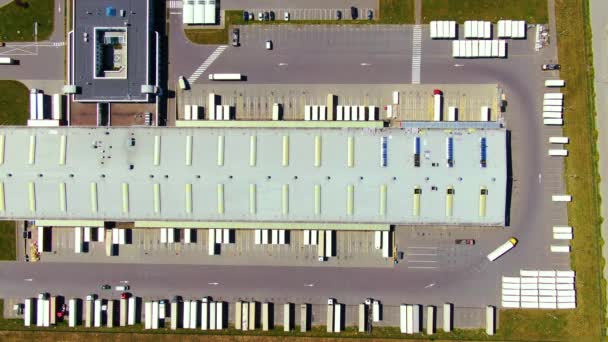 Widok z lotu ptaka magazynu towarów. Centrum logistyczne w strefie przemysłowej miasta z góry. Widok z lotu ptaka załadunku ciężarówek w centrum logistycznym - Materiał filmowy, wideo