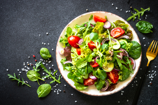Grüner Salat, frische Salatblätter und Gemüse auf weißem Teller. - Foto, Bild