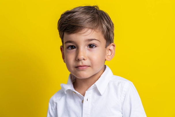 Vista frontale del piccolo ragazzo caucasico di quattro anni in piedi di fronte allo studio giallo girato bambino serio - Foto, immagini