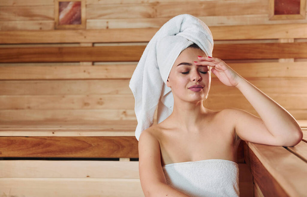 Young beautiful woman in white towel have a rest in the sauna. Conception of bodycare. - Φωτογραφία, εικόνα