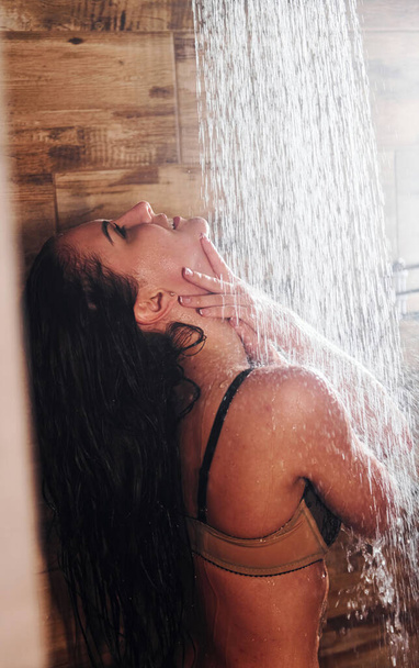 Pretty brunette with sexy slim body type in underwear taking a shower in spa. - Fotó, kép