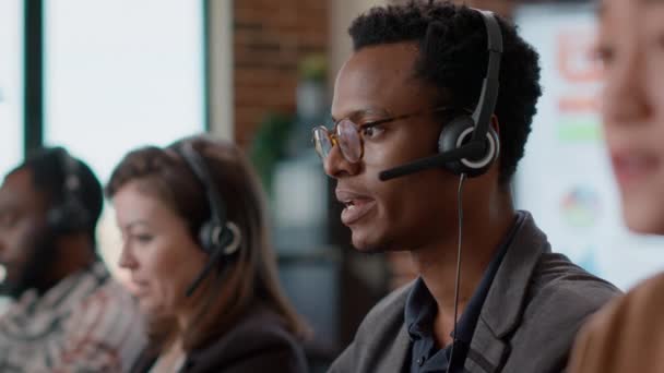 Afričtí američtí pracovníci vedou konverzaci na sluchátkách s klientem - Záběry, video