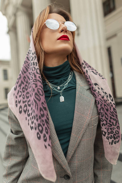 Cooles stylisches Hipster-Mädchen mit roten Lippen in modischer Sonnenbrille und elegantem grauen Anzug mit Schal auf dem Kopf spaziert durch die Stadt - Foto, Bild