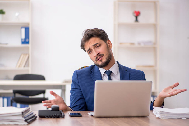 Young male employee unhappy with excessive work in the office - Photo, Image