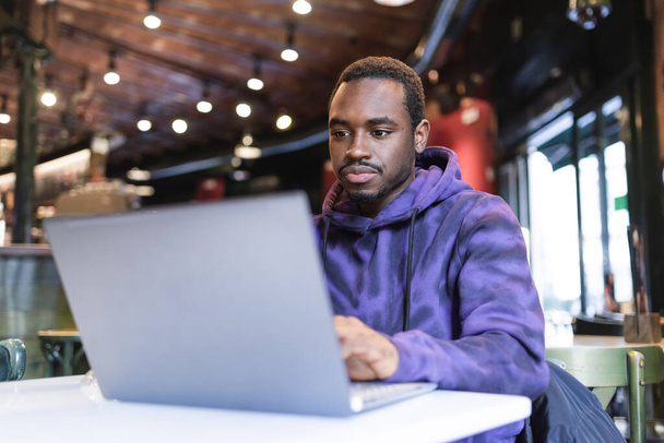 Serious black man working on laptop in cafe - Foto, afbeelding