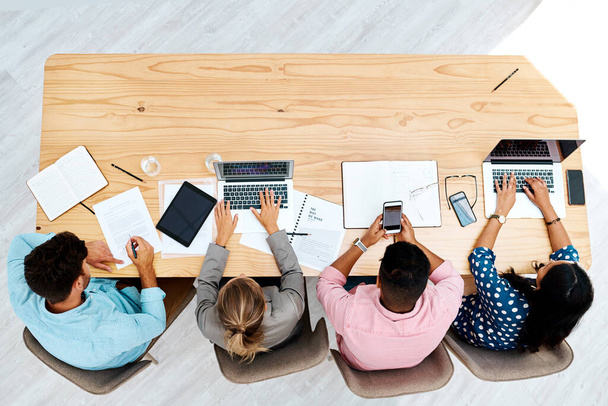 Everyones very busy in this shared working space. High angle shot of a group of businesspeople working together at a table in an office. - Photo, Image