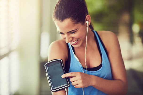 Nothing like a workout playlist to get you started. Shot of a young woman starting her playlist before working out. - Zdjęcie, obraz