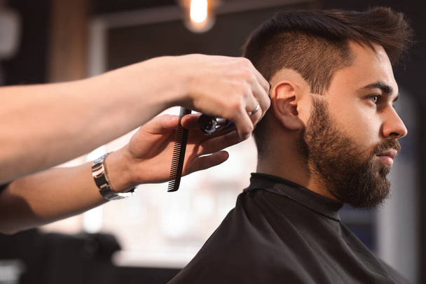 Professional hairdresser working with client in barbershop - Foto, Imagen