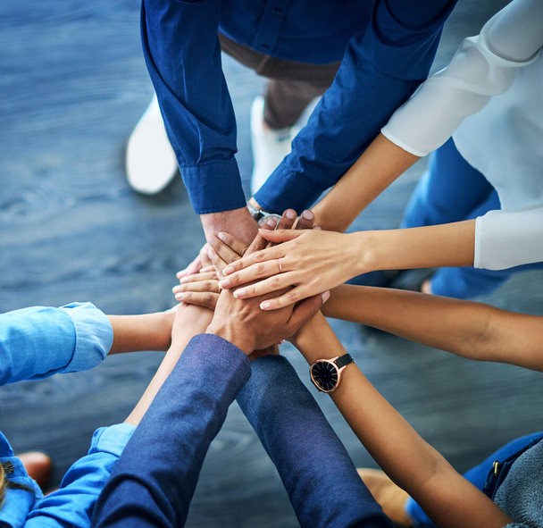 Lets awaken the team spirit. High angle shot of a group unrecognizable businesspeople joining their hands together in unity. - Foto, imagen