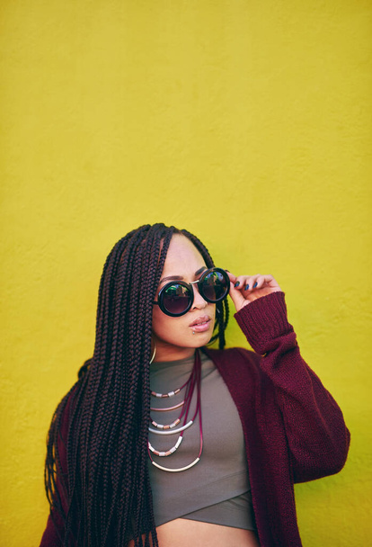 Cool and she knows it. Shot of a young woman wearing sunglasses against a green background. - Zdjęcie, obraz
