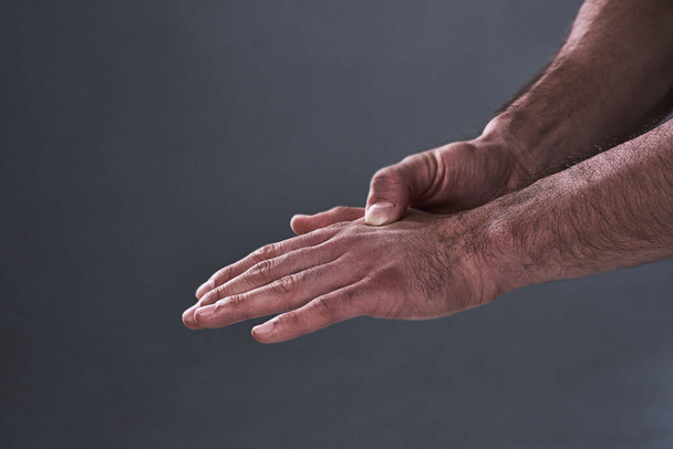 An injured hand will put an end to most workouts. Shot of an unrecognizable man rubbing his injured hand during a workout. - Fotografie, Obrázek